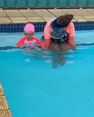 Instructor talking to young swimmer on edge of pool